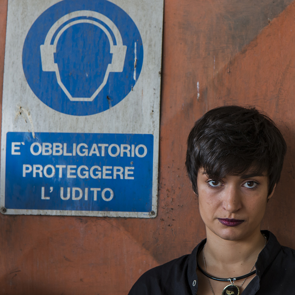 Ritratto di Gaia Marlino con un'insegna provocatoria legata all'udito.